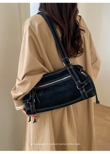 Back view of a large black suede tote bag with white contrast stitching on a model