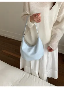 Close-up of a light blue leather hobo bag with silver buckle worn by a model in a studio