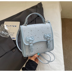 Detail of light blue crossbody bag featuring silver star print and twin 3D bow accents