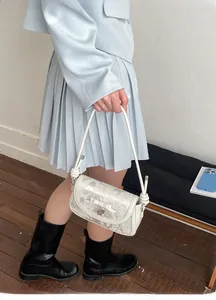 Détail du sac à main blanc imprimé marbre avec nœud décoratif et pendentif cœur en métal