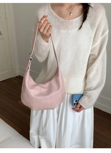 Pink leather hobo bag with adjustable wide strap shown on a model in a casual setting