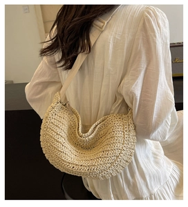 Dettaglio di una borsa hobo in paglia intrecciata beige con tracolla in tessuto coordinata