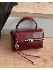 Detail der burgunderroten Ledertasche mit silbernem Herzanhänger und Drehverschluss