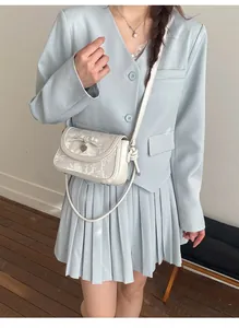 Sac bandoulière chic en cuir blanc avec nœud et pendentif cœur porté sur un mannequin
