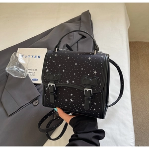 Detail of black bow and star print messenger bag with adjustable metallic buckle closure