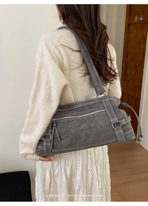 Detail of grey shoulder tote bag showing white contrast stitching and zip pocket