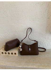 Close-up of brown litchi grain leather bag set with silver clasp on stone surface