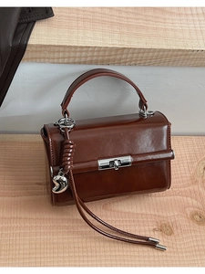 Nahaufnahme braune Vintage-Handtasche mit silbernem Drehverschluss und Herzanhänger