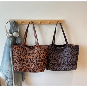Vue détaillée de grands sacs cabas léopard marron et gris suspendus à des crochets