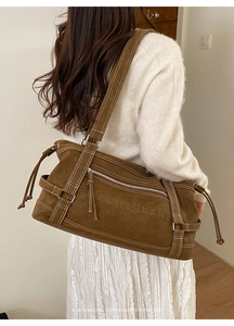 Detail view of brown faux suede shoulder bag featuring contrast stitching and tassel zipper