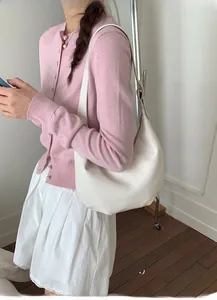 Detail view of a white vintage hobo bag styled with a pink cardigan and pleated skirt