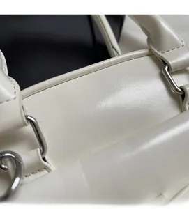 Detail of white leather texture and silver metal ring hardware on minimalist handbag