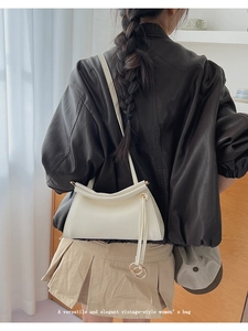 Detail of minimalist cream leather shoulder bag with metallic double ring charm accessory