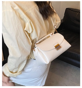 Gros plan d'un sac à main blanc en cuir avec boucle dorée porté par un mannequin