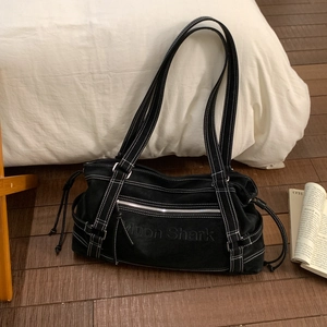 Detailed close-up of a black canvas tote bag featuring white contrast stitching and zippers