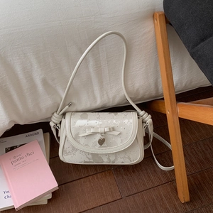 Détail du sac à bandoulière blanc avec nœud papillon, pendentif cœur et imprimé marbre