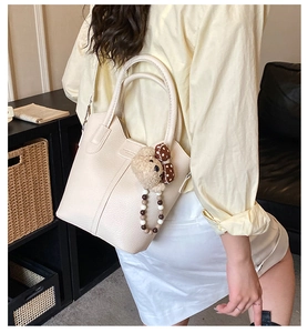 Detail view of cream bucket bag with lychee texture leather and cute bear charm pendant