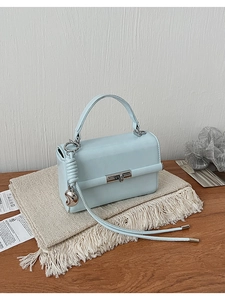 Detailansicht der hellblauen Handtasche aus Leder mit Metalldrehverschluss und Herzanhänger