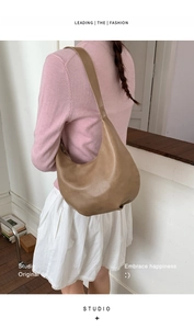 Brown leather hobo bag worn by a model showing high-capacity design and wide strap