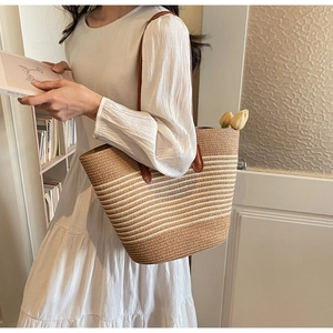 Detail of handwoven striped straw tote with leather handles and spacious interior