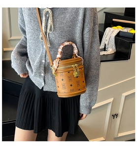 Détail du sac seau marron avec motifs d'ours et poignée ornée d'un foulard en soie