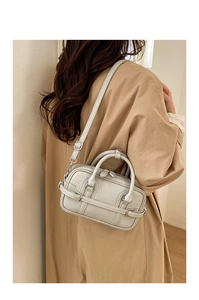 Sac Boston en cuir gris clair porté par un mannequin en trench-coat de couleur camel