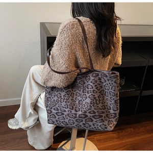 Détail du grand sac cabas à imprimé léopard avec anses en cuir brun sur l'épaule