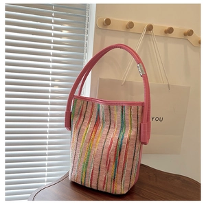 Detail of colorful striped tweed bucket bag with pink leather handle and metal buckle