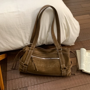 Detail of dark brown matte leather tote featuring Nuon Shark embossing and white stitching