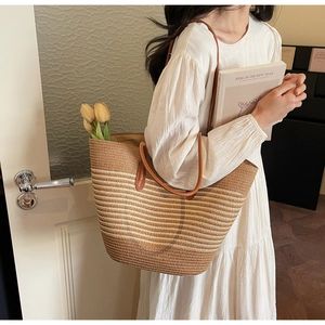Detail of striped woven straw tote bag with brown leather straps and tulip decor