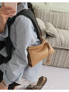 Detail of light brown vintage leather shoulder bag with gold ring hardware and fold design
