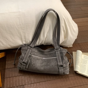 Detail of dark grey vintage tote bag with vertical straps and silver zipper on wood floor