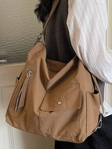 Brown minimalist large tote bag with utility pockets shown on a female model
