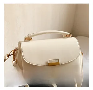 Détail d'un mini sac en cuir blanc avec poignée supérieure et fermoir doré magnétique