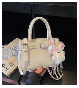 Detail of white faux leather crossbody bag with lychee texture and cute bear pendant