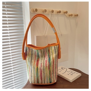 Detail shot of the knit texture and vibrant vertical stripes on the canvas bucket bag