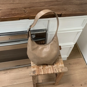 Detail view of khaki hobo bag with wide adjustable strap and silver metal eyelets