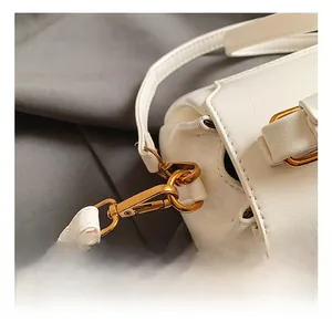 Gros plan des coutures du cuir blanc et du crochet métallique doré rétro du sac