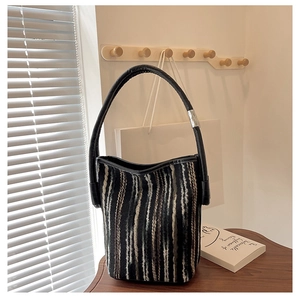 Close-up of knit bucket bag featuring vertical stripes and a black leather handle