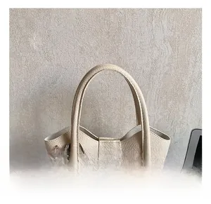 Close-up of comfortable handles and textured leather on this beige bucket bag