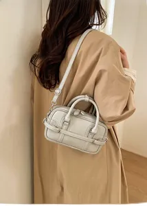 Détail du sac à bandoulière beige élégant avec brides décoratives et boucle métallique