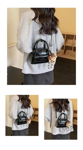 Detailed view of black patent leather pillow bag with bow and teddy bear charm