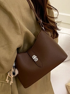 Deep brown pebble leather bucket bag with silver metal buckle and soft plush charm accessory