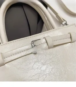 Close-up of white crossbody bag with oil wax leather texture and silver buckle detail