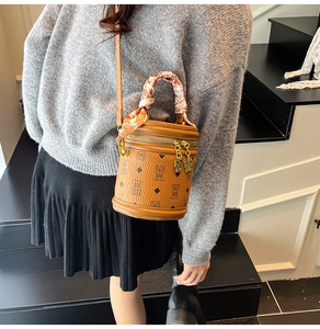Détail d'un sac bandoulière cylindrique marron avec imprimé ours et poignée en foulard