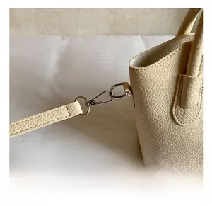 Detailed close-up of cream-white lychee leather handbag with silver rotating metal hook fastener