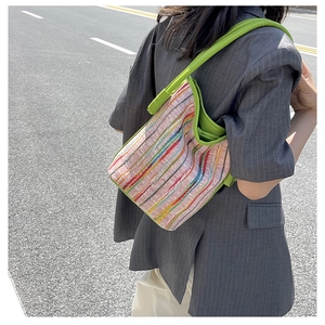 Street style view of pink striped canvas tote bag with vibrant green shoulder strap