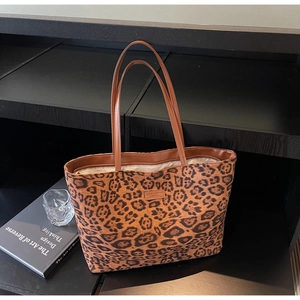 Gros plan du sac cabas léopard avec anses en cuir marron et petit logo de marque