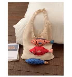 Détail du sac cabas en tricot blanc cassé avec breloques poissons 3D et texture crochet