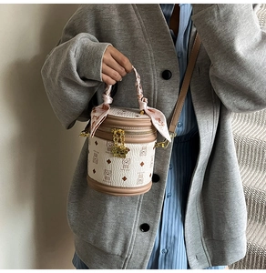Détail du sac seau crème avec motifs dessins animés et poignée ornée d'un foulard